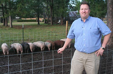 
                    Craig Baker stands in front of the pig pen he's built. The land owned by the Katy Islamic Association is directly behind the pen.
                                            (Michael May)
                                        