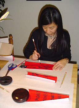 
                    Wendy writes auspicious sayings ("Fai Chun") on red paper using ink she made herself.
                                            (Charlie Schroeder)
                                        