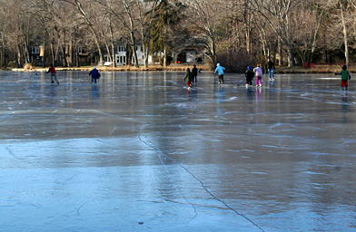 
                    Neighborhood kids skating on Nash's Pond the only weekend skating conditions were good this winter. The long pressure crack in the foreground is a sign that the ice is deeply frozen. And the white house in the background is where Hillary used to trespass to get on the pond.
                                            (Stacy Fowle)
                                        