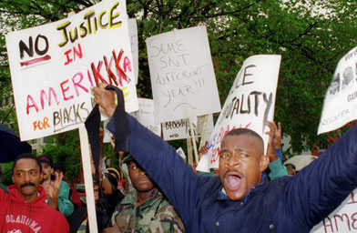 
                    Protestors upset over the verdict in the Rodney King beating trial in Simi Valley, Calif., demonstrate outside of the Fraternal Order of Police headquarters in Washington D.C. 30 April 1992. The acquittal of four police officers in the beating of King led to widespread anger and rioting.
                                            (Paul J. Richards / AFP / Getty Images)
                                        
