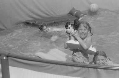 
                    Jane Bratton, waving in the photo, and her two siblings, in the backyard pool that they built with their mother.
                                            (Jane Bratton)
                                        