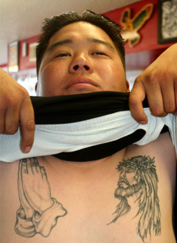 
                    Specialist Daniel Lee has images of Jesus and praying hands tattooed on his chest before leaving for Iraq.
                                            (Michael May)
                                        