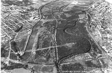 
                    An aerial photograph from the late 1920s showing the channelization of the Trinity River through Dallas. The original river channel is on the right, meandering right by downtown Dallas in the far upper right.  Much of the old river channel is now buried, or serves as a run-off ditch.
                                            (Courtesy of Dallas/Texas Historical Archives, Dallas Public Library)
                                        