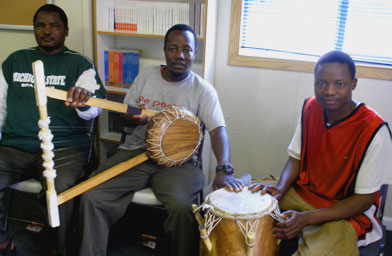 
                    Omar Abdirahaman (center) and two other Somali Bantu men sit with the instruments they play at cultural gatherings and community celebrations. They made the guitar in the center themselves using motorcycle brake wire, donated calf skin and bed posts.
                                            (All photos by Ann Heppermann, Kara Oehler and Laurel Simmons)
                                        