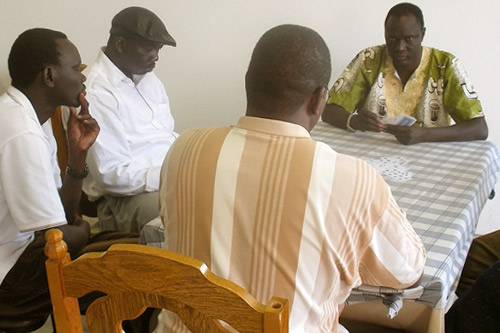 
                    Sudanese refugees and asylum seekers play cards at the Sudanese Center of Omaha. Malakal Goak is second from left in the white shirt and black hat.
                                            (Kara Oehler & Ann Hepperman)
                                        