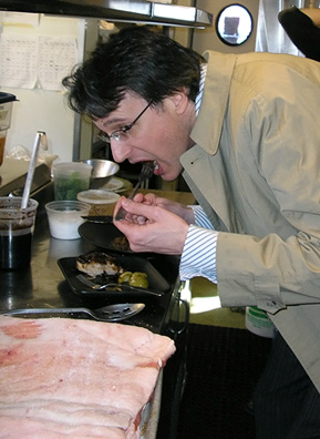 
                    Weekend America co-host Bill Radke takes a bite of Reusing's pork belly dish just inches away from a slab of raw pork belly.
                                            (Suzie Lechtenberg)
                                        