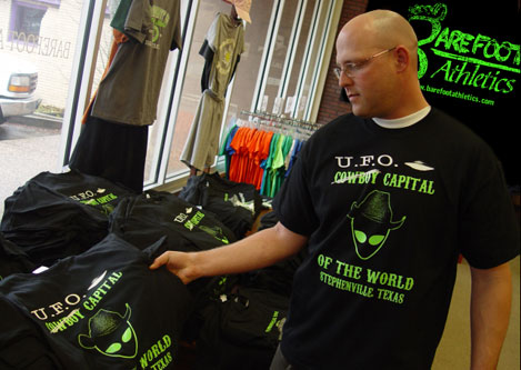 
                    Barefoot Athletics store manager Matt Shaw, in his normal hue, showing off their popular UFO sighting shirts.
                                            (Joaquin Cortez)
                                        