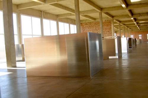 
                    Donald Judd's 100 untitled works in mill aluminum at the Chinati Foundation. The building that houses them is known as "The Block," because it measures one full city block. Judd first rented one of these two former army buildings when he first arrived in Marfa in 1971. He later purchased the entire property In 1974. The Judd/Chinati Foundations have maintained Judd's living and work spaces as permanent installations since his death in 1994.
                                            (Neille Ilel)
                                        