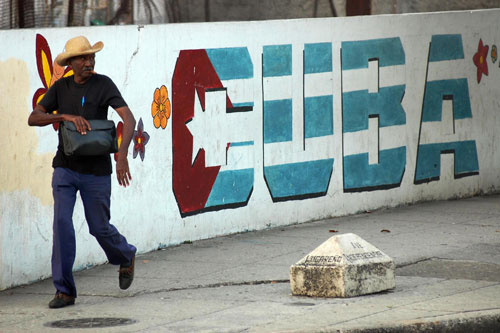 
                    A pedestrian passes by a huge graffiti in Havana on Feb. 22, 2008. The race to succeed the outgoing Fidel Castro includes a few candidates, but the solid favorite remains Fidel's brother Raul Castro, who inherited the interim presidency following the leader's operation in July 2006.
                                            (STR/AFP/Getty Images)
                                        