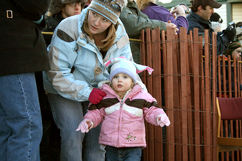 
                    A little Alaskan waits with mom for the Fur Rondy Outhouse Races to begin.
                                            (Photo Credit: Anchorage Convention &Visitors Bureau/Cady Lister)
                                        