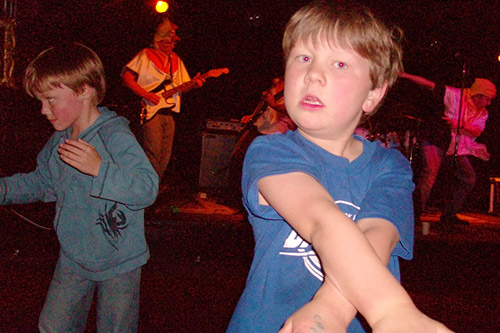 
                    Charlie (foreground) and Ryan rock out on the dance floor while their fathers rock out on stage.
                                            (Jill Moe)
                                        