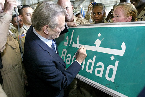 
                    Former Secretary of Defense Donald Rumsfeld signs a Baghdad road sign during a visit to Iraq shortly after the U.S.-led invasion in 2003.
                                            (Luke Frazza/AFP)
                                        