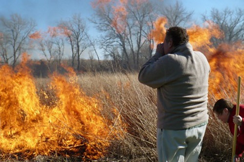 
                    The dry, tall grass flares up in an instant. Mike Estep takes pictures while his wife, Jerry lights the fire.
                                            (Sylvia Gross)
                                        