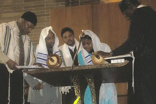 
                    Tammy McCullough, studying to be a rabbi, reads from the Torah with temple leaders.
                                            (Photo courtesy Temple Beth Shalom)
                                        