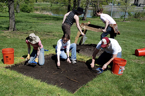 
                    This shallow unit is one of the four squares being excavated in the park. Students Sarah Pickman, Caitlin Wylie and Dana Snitzky use trowels to dig through the topsoil, while Teacher's Assistant Mary Leighton and student Darian Gier sift through buckets of dirt for artifacts.
                                            (Rebecca Graff)
                                        