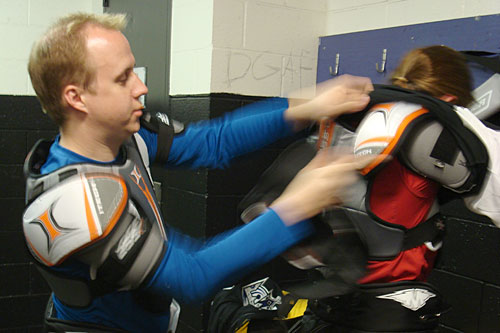 
                    Benjamin Salisbury helps his wife Kelly get suited up before their hockey class. "The first day, it was like you were literally just a knight at Medieval Times," Benjamin Salisbury says. "You're literally just weighed down."
                                            (Charlie Schroeder)
                                        