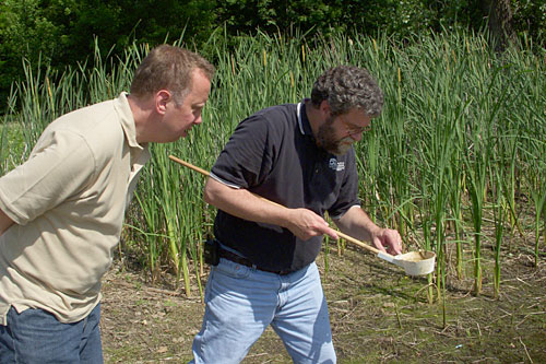 
                    John Moe and Mike McLean use a "dipper" to examine a pond that is a popular hangout for mosquitoes.
                                            (Courtesy John Moe)
                                        
