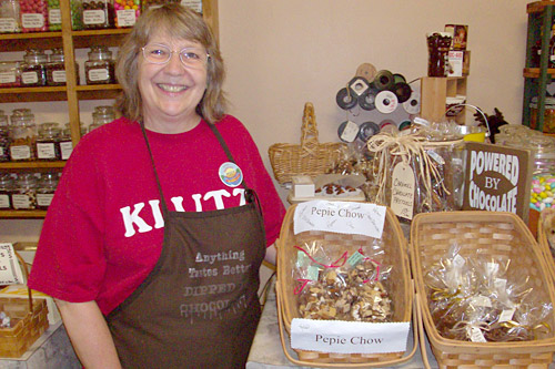 
                    Jil Garry in front of a display of Pepie Chow. It's a mixture of nuts and chocolate intended for Pepie seekers trying to collect the $50,000 reward being offered for people who can prove Pepie's existence.
                                            (John Moe)
                                        