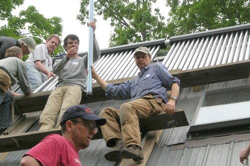 
                    The volunteers form an assembly line to pass the light-weight solar tubes up the roof to where they're set into place.
                                            (Shannon Mullen)
                                        
