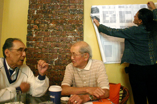 
                    Long-time residents of Seattle's Japantown Joe and Roy discuss the old neighborhood in the teahouse as hotel owner Jan Johnson hangs up a map of the old Japantown.
                                            (David Weinberg)
                                        