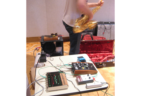 
                    Electronics Table: Elliot dashing from his collection of effects pedals to join his NOMO compatriots in the horn section.
                                            (Angela Kim)
                                        