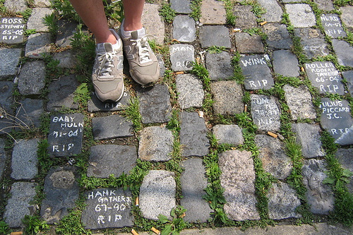 
                    Yong Lee stands among several of the of the 30 or so cobblestones that make up his street memorial  in Philadelphia, Pa. Among the people remembered here are former Loyola Marymount University forward Hank Gathers. He died during a game from complications of an abnormal heart.
                                            (Jonathan Menjivar)
                                        