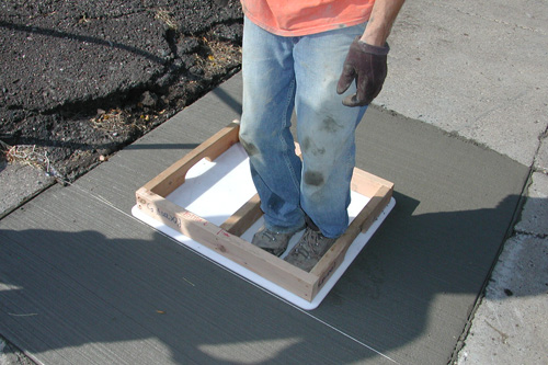 
                    Holding the mold in place to make the sidewalk impression.
                                            (Chris Roberts)
                                        