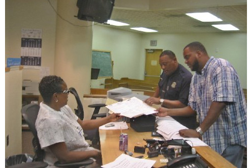 
                    Officer Owen talks to Court Clerk Cheryl Sharpley. Joining them in plain clothes is Officer Robert Mingus, the great-grand nephew of jazz great Charles Mingus. When he's off duty, Officer Mingus teaches fathers about responsible parenthood. He worries about the effect of the foreclosure crisis on Detroit neighborhoods.
                                            (Desiree Cooper)
                                        
