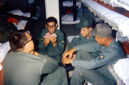 
                    Troops aboard the Walker play cards to pass the time. Although gambling was not permitted, some soldiers and Marines accumulated large sums of winnings from the pastime. As some troops remarked about disregarding the regulation, "What were they going to do, send us to Vietnam?"
                                            (Courtesy 1st Squadron, 1st Cavalry Regiment)
                                        