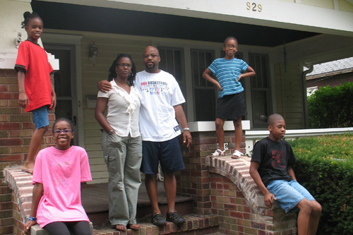
                    The Gilbert family in front of their old house in Bloomington, Ill.  Their new house is in the next town, Normal. The children, clockwise, from left:  Nia, age 9: Ayanna, age 7, Mark Jr., age 12, Imani, age 11.
                                            (Laurie Stern)
                                        