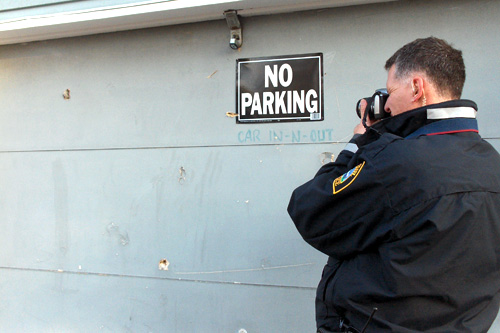 
                    Officer Lundquist gets close up shots of stray bullets lodged in this garage.
                                            (Marc Sanchez)
                                        
