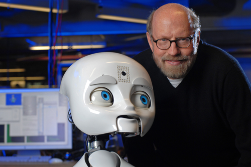 
                    David Kirkpatrick, chairman of Plymouth Rock Studios, with Nexi, a robot developed by MIT Media Lab's Personal Robots research group.
                                            (Sam Ogden)
                                        