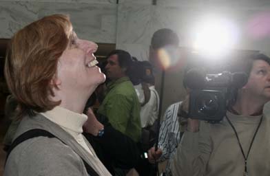 
                    Cindy Sheehan at the Senate Hart Building, looking up at a banner that reads "We Will Not Be Silent."
                                            (Michael May)
                                        