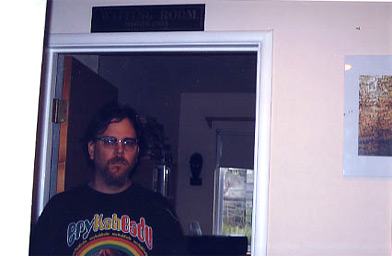 
                    Poet Joe Wenderoth, under an antique sign from the Jim Crow era.  It reads "Waiting Room.  Whites Only."  It hangs over the door to his wife, Romana's study.  She wouldn't have been let in the whites only waiting room 50 years ago.
                                            (Krissy Clark)
                                        