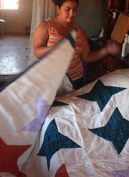 
                    A woman shows off her star-embroidered quilt, one of the 15 that De Narvaez will bring back to the sell in the U.S.
                                            (Michael May)
                                        