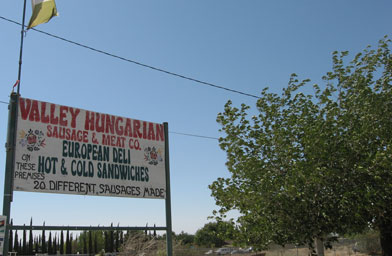 
                    The sign for Maria Watson's shop along Pearblossom Highway swings in the hot desert wind. Many weekend drivers speed past it the first time, then make a 360-degree turn for a sandwich.
                                            (Eve Troeh)
                                        