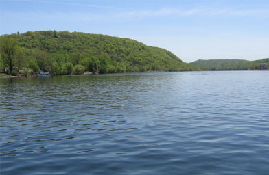 
                    Washington used the big hill on the left, Goat Hill, as a natural hiding place for his boats from the Hessian troops. These hilltops also housed spies, who were prepared to set off a series of signal fires all the way to the city warning the Continental Congress of an attack.
                                            (Hillary Frank)
                                        