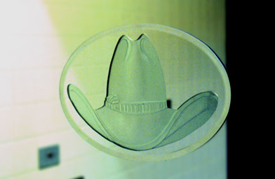 
                    In the men's room by baggage claim at the Austin airport, you can "try on" a hat--or a wig in the women's restroom.  Etched glass hat by Jill Bedgood.
                                            (City of Austin Art in Public Places (AIPP))
                                        