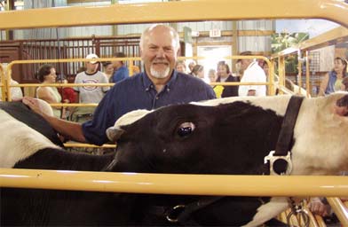 
                    Miracle of Birth Center co-founder Florian Ledermann shows off a bovine buddy.  The night before, Ledermann had to sleep in the Center to await any births, and he says this cow came over to sniff his ear, drool on him, and then hunker down next to him.
                                            (Annie Baxter)
                                        