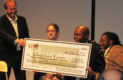 
                    Public Radio Exchange Executive Director Jake Shapiro presenting the Public Talent Quest winners Rebecca Watson, Glynn Washington, and Al Letson with $10,000 each.
                                            (Angela Kim)
                                        