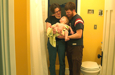 
                    Jenny Hitch and Josh Moore hold baby Jonas in their new bathroom. Their old one featured a toilet held in only by its pipes.
                                            (John Moe)
                                        