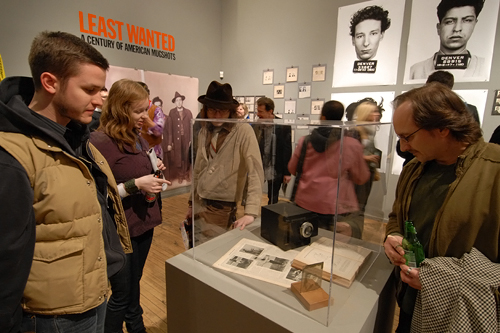 
                    Attendees to the "The Least Wanted" opening night at the Intuit Center for Outsider Arts look at an old police camera and glass negative.
                                            (Courtesy Steidl & Partners Publishing)
                                        