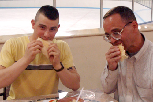 
                    Cpl. Cory Bailey (left) and LTC Scott Winchester at an enormous sparkling mall in the city of Doha eating hummous for the first time. Note the ice-skating rink behind them.
                                            (Orly Halpern)
                                        